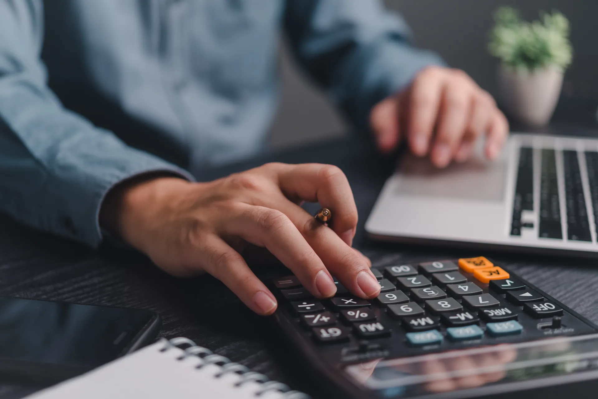 Accountant working with a calculator and laptop at a desk