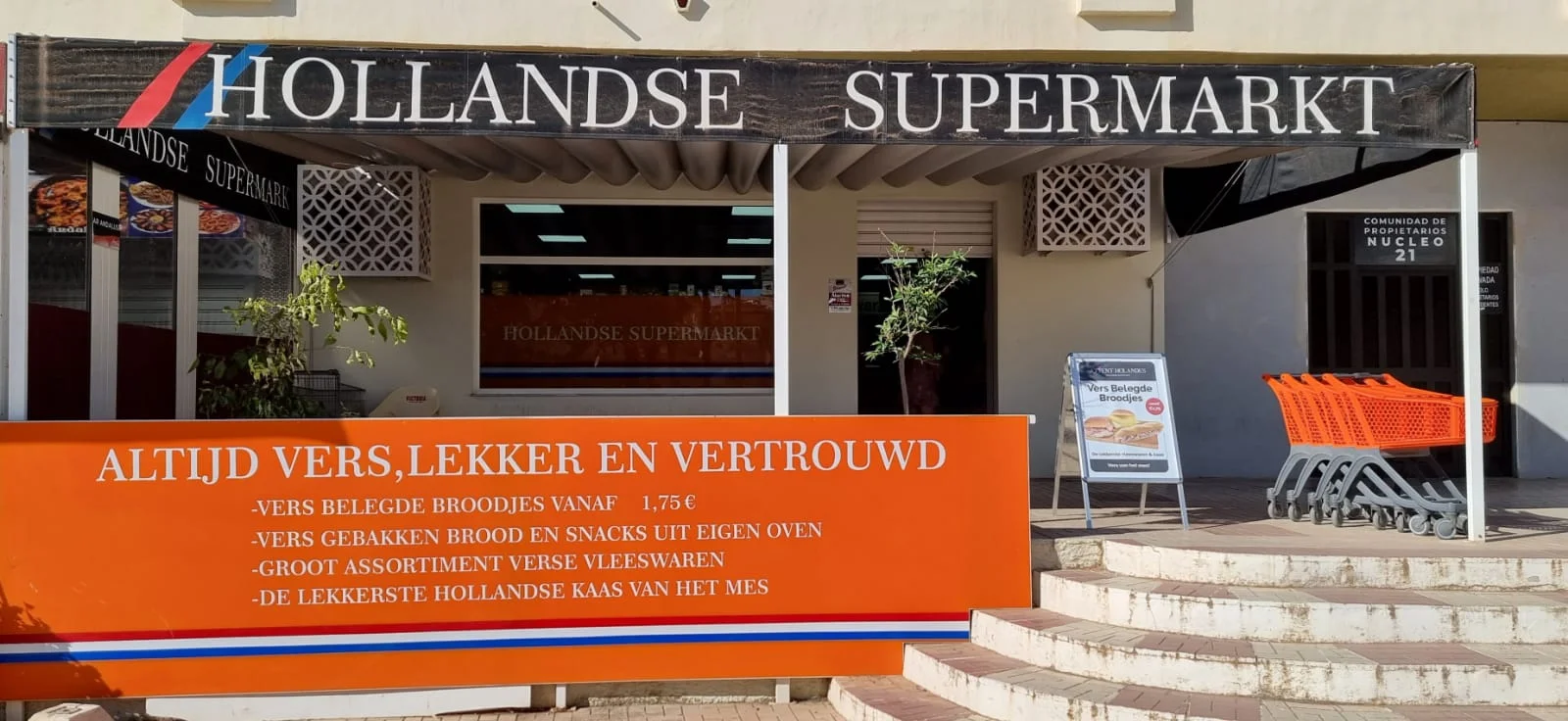 The Hollandse Supermarkt awning of Attent Holandés in Torremolinos, orange trolleys by the steps