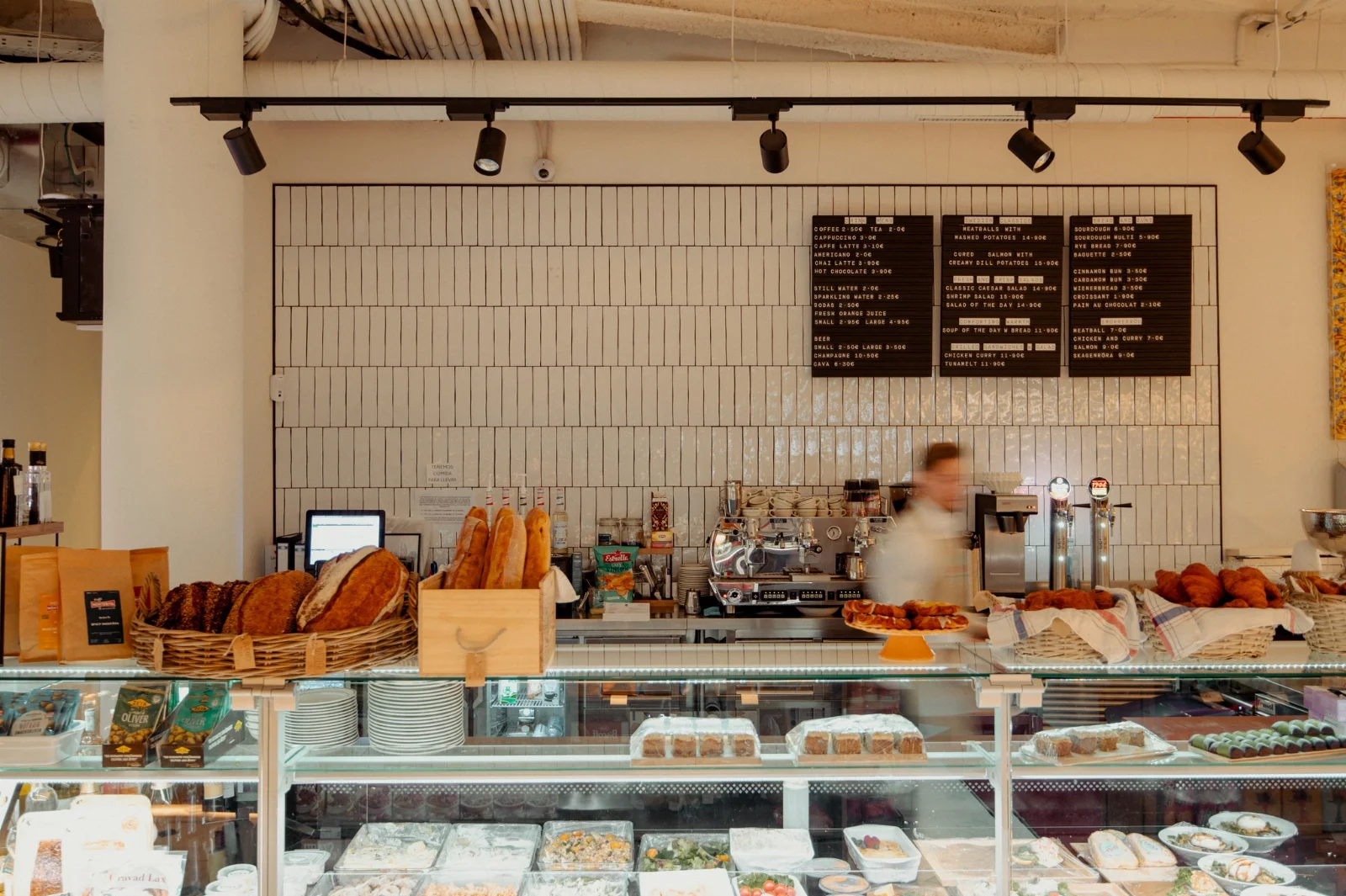 The deli counter inside Baccara Deli & Market, with the menu boards and fresh bread at Forum Marbella