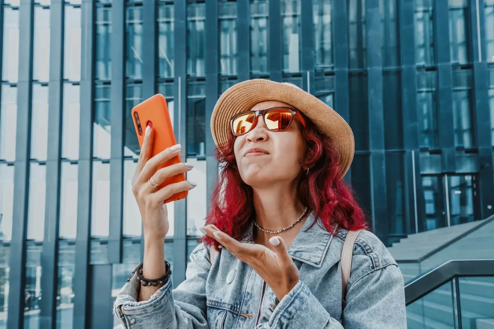 Frustrated woman in a sun hat checking her mobile phone for signal outside
