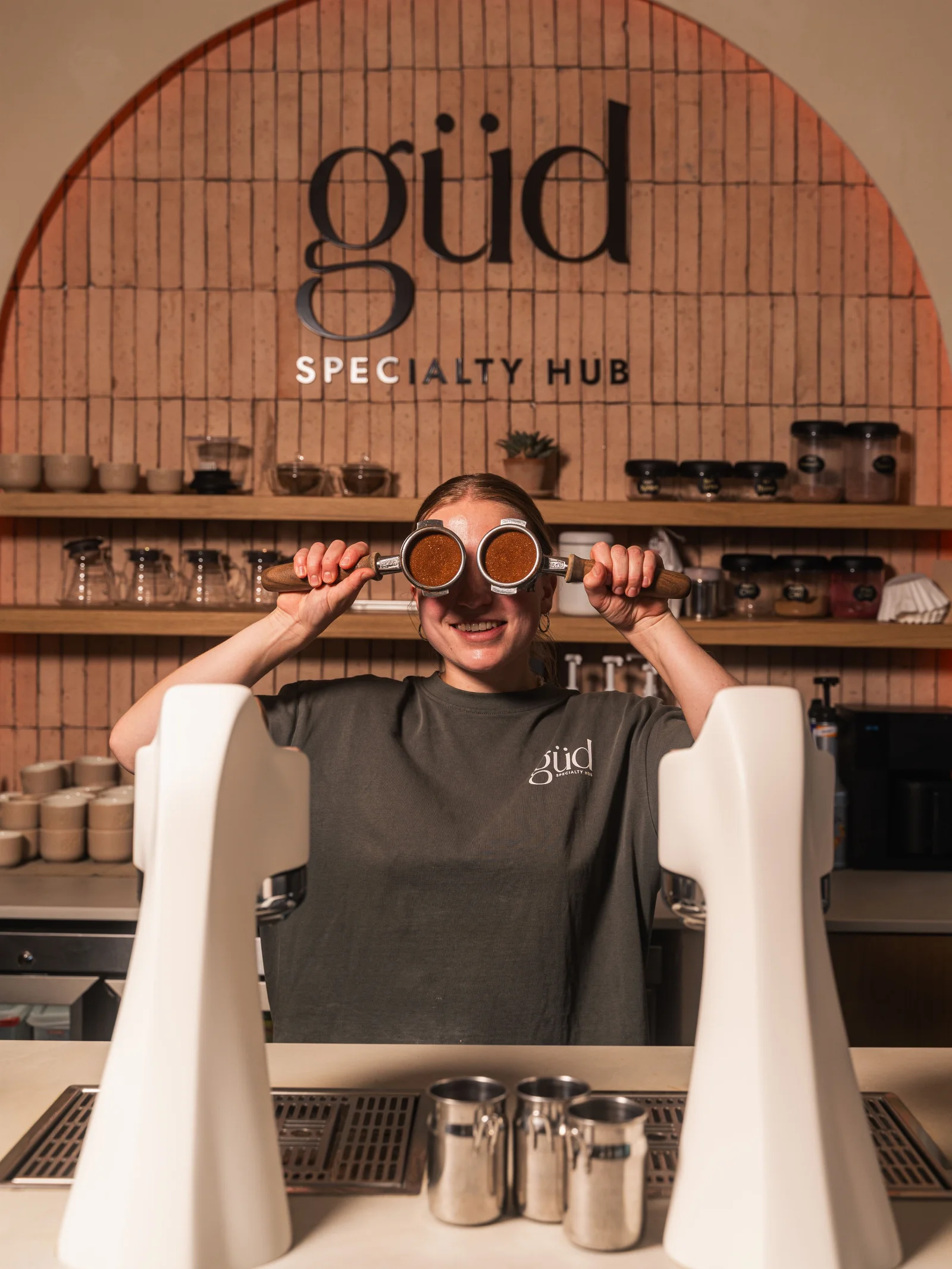 The güd specialty hub logo arch behind the coffee counter in San Pedro