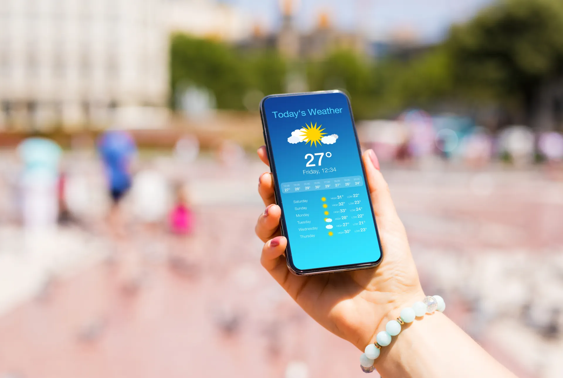 Hand holding a smartphone showing a sunny 27-degree weather forecast