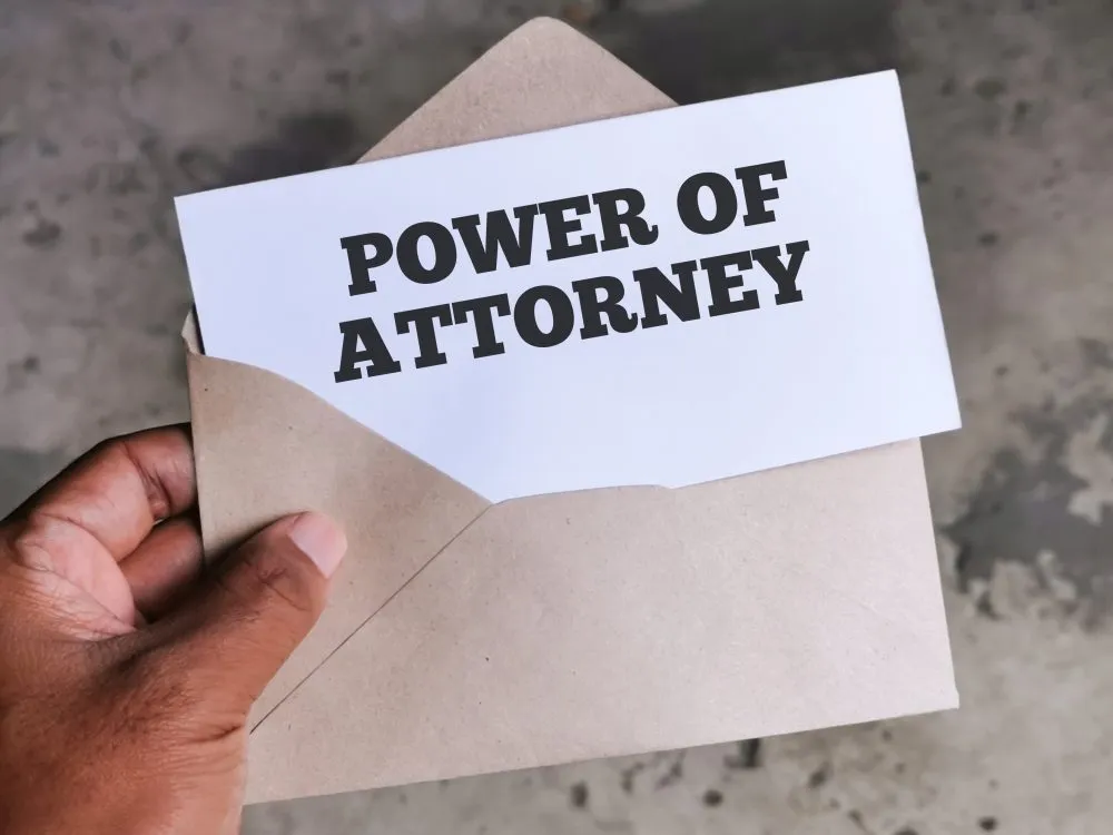 Hand holding an envelope with a card reading Power of Attorney
