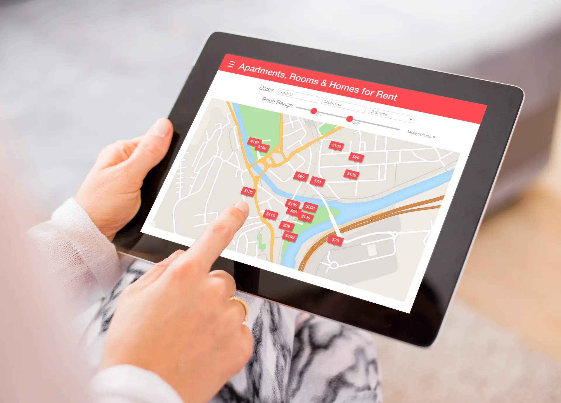 Hands holding a tablet showing a rental property map with price markers