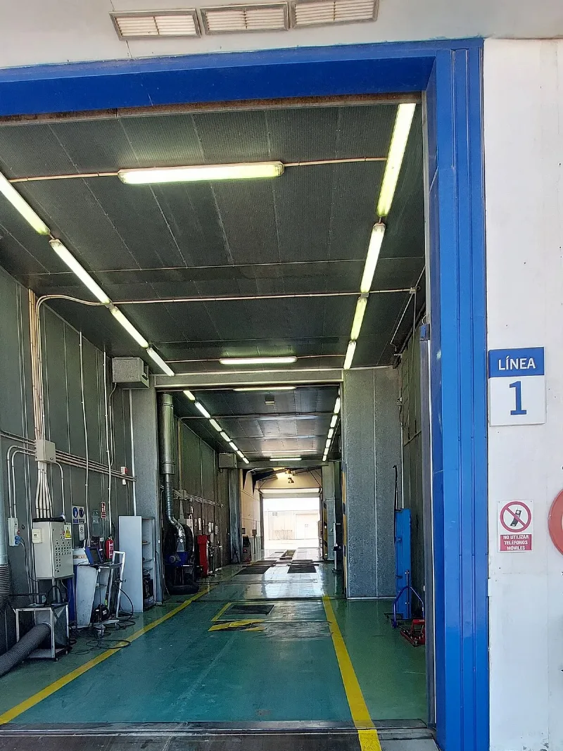 The open door of inspection lane 1 at a Veiasa ITV station in Albox, the lane running ahead under strip lights