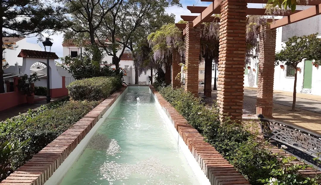 Long fountain and brick pergola draped with wisteria in Cancelada's town square