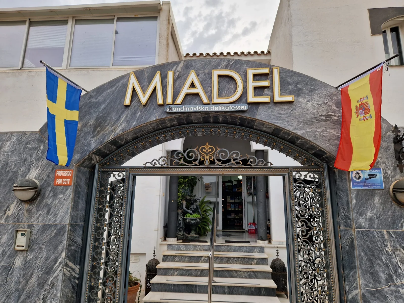 The marble arch entrance of Miadel in Nueva Andalucía, with the Swedish and Spanish flags over the gates