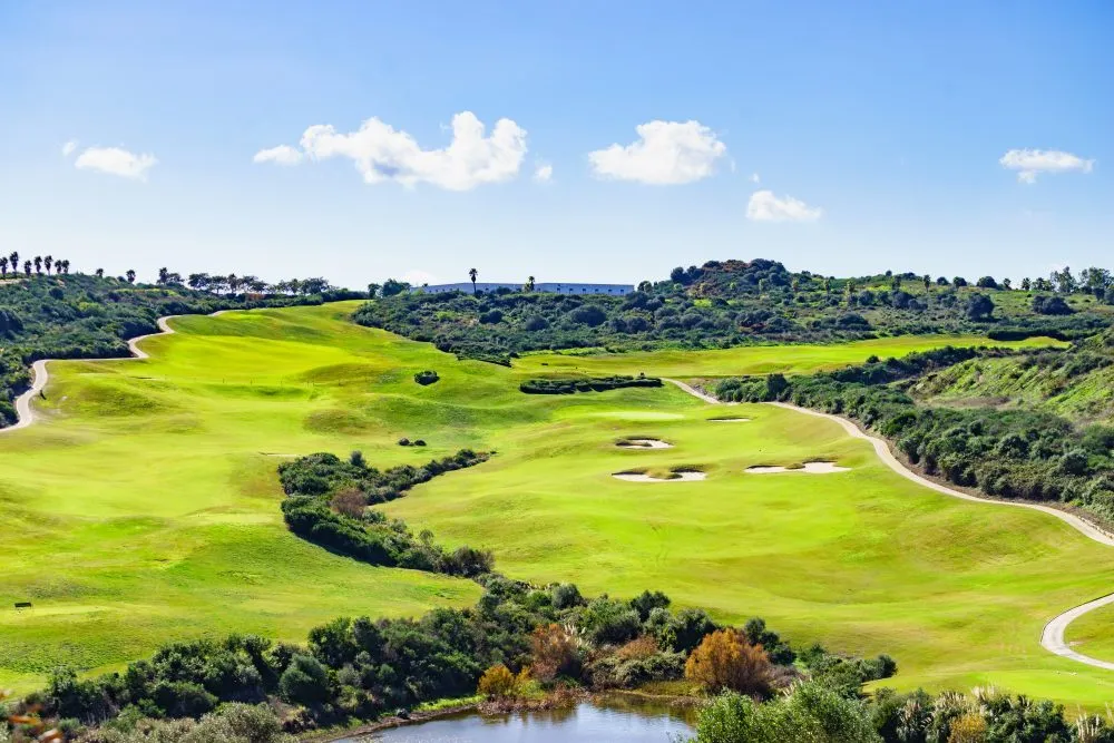 Rolling green golf fairways with bunkers under a blue sky in Sotogrande